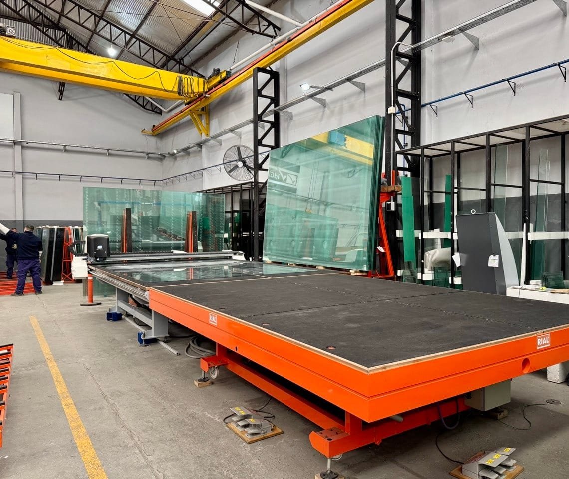 Operario cortando una plancha de vidrio en la mesa de corte de la planta de VidGlass